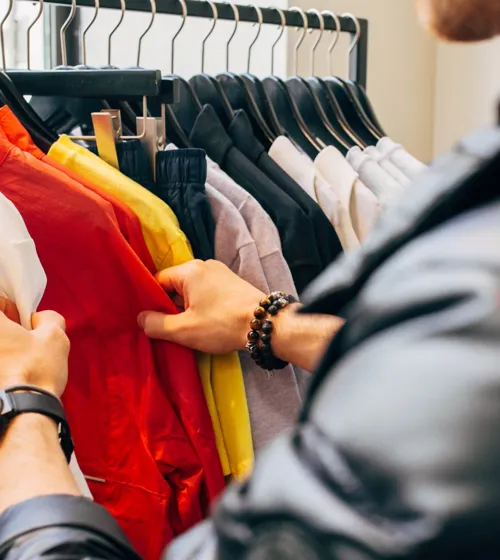 Mains d’un homme en train de magasiner des chemises sur un présentoir.