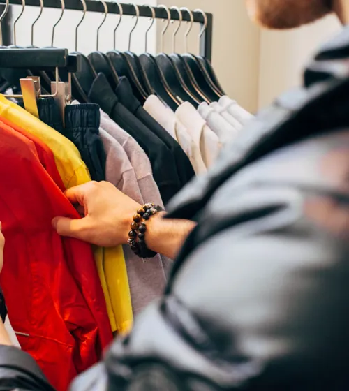 Mains d’un homme en train de magasiner des chemises sur un présentoir.