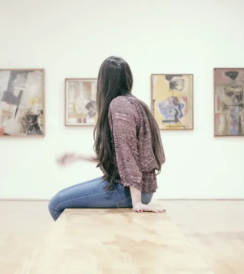 Femme assise admirant des œuvres dans un musée.