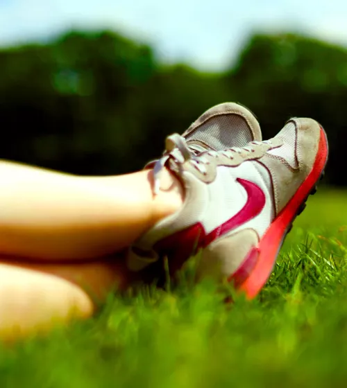 Pieds croisés, avec souliers de course, étendus sur le gazon.